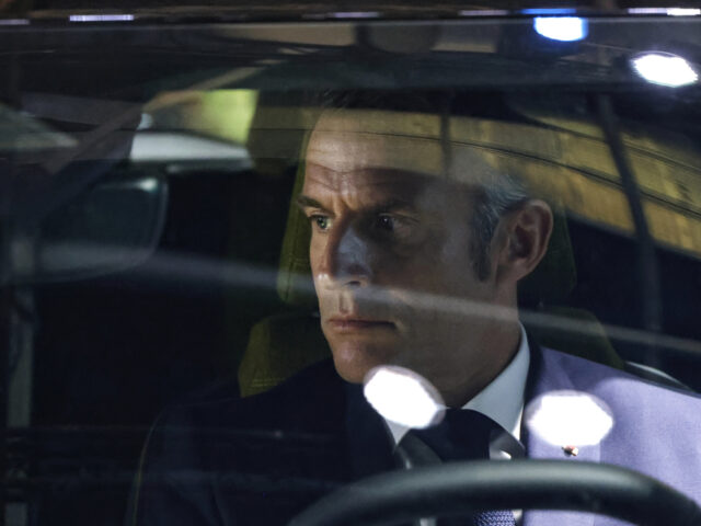 Spotlights are reflected in the windscreen as French President Emmanuel Macron sits in a c