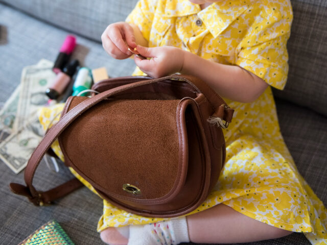 Toddler playing with purse on sofa