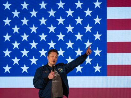 Elon Musk speaks before a flag