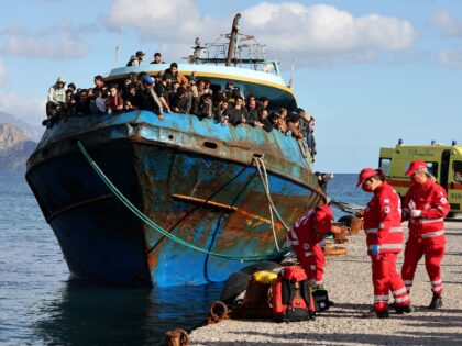 Hellenic Red Cross rescuers and health workers stand by a boat carrying some 400 refugees