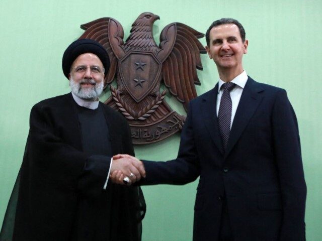 Syria's President Bashar al-Assad (R) shakes hands with his Iranian counterpart Ebrahim Ra