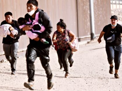 YUMA, ARIZONA- MAY 20: Immigrants, some carrying small children, run to cross through a ga