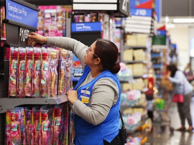 An employee adjusts a price label for Barbie dolls displayed for sale ahead of Black Frida