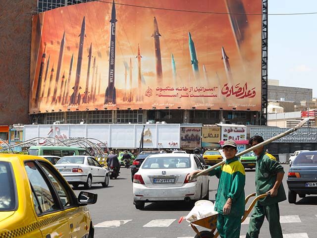 Motorists drive their vehicles past a billboard depicting Iranian missiles in Tehran on Ap