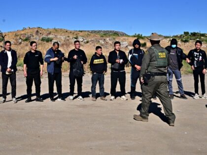 A large group of Chinese migrants, including three from Bangladesh, line up for a Customs