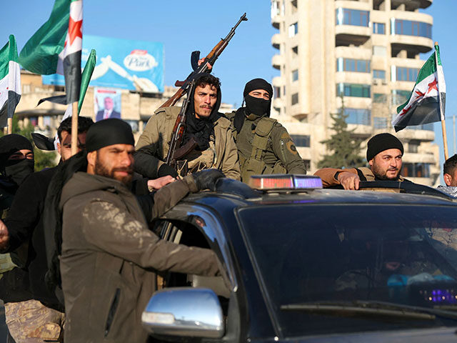 Anti-government fighters brandish their guns as they ride a vehicle in Syria's northern ci