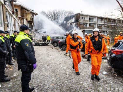 Policemen (L) and firemen gather outside a partially collapsed residential building follow