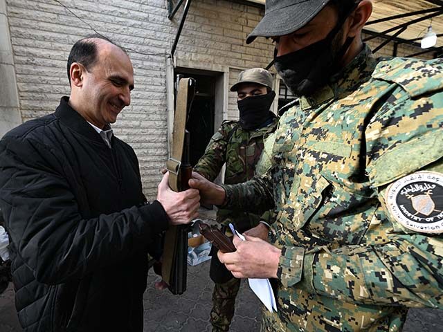 A soldier from Hayat Tahrir al-Sham's "Salvation Government" (R) collects the weapon of a