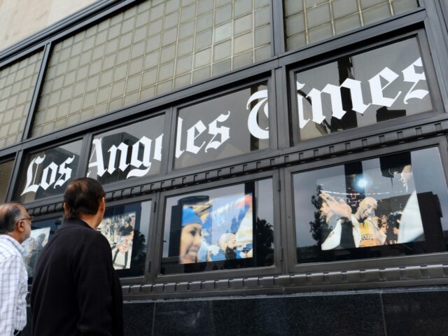 Pedestrians look at news photos posted outside the Los Angeles Times building downtown Los