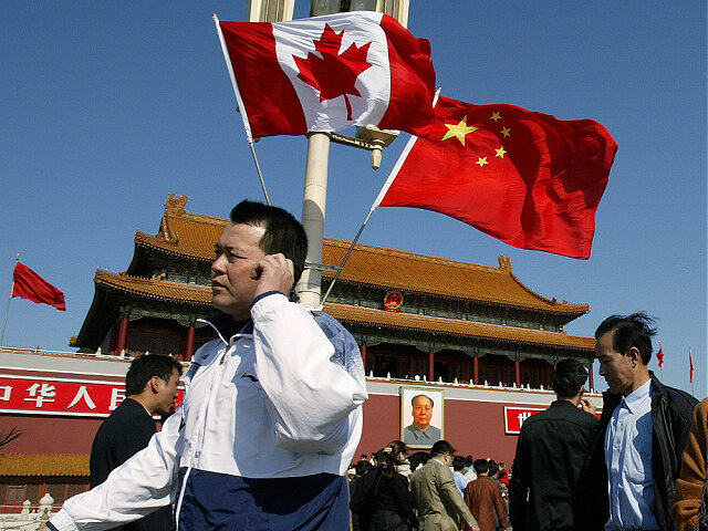 BEIJING, CHINA: A man walks past flags of Canada and China in front of Tiananmen Gate in B