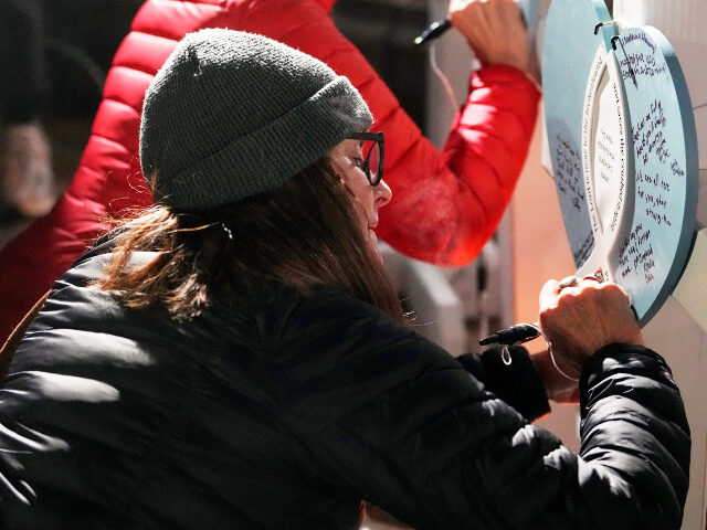 Supporters sign crosses during a candlelight vigil Tuesday, Dec. 17, 2024, outside the Wis