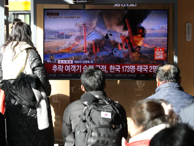 People watch the news regarding the plane crash at Seoul station on December 29, 2024 in S