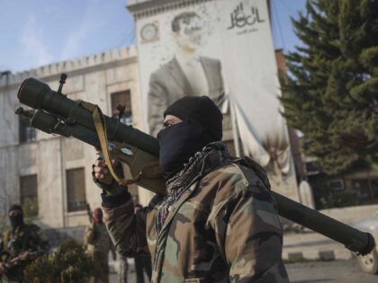 A Syrian opposition fighter holds a rocket launcher in front of the provincial government