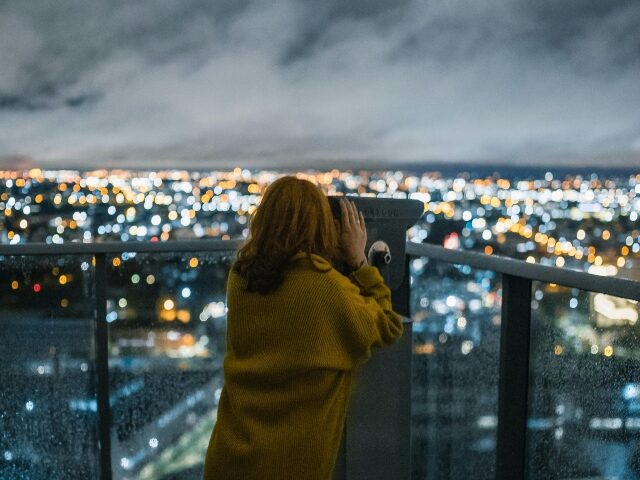 Woman using binoculars in the city