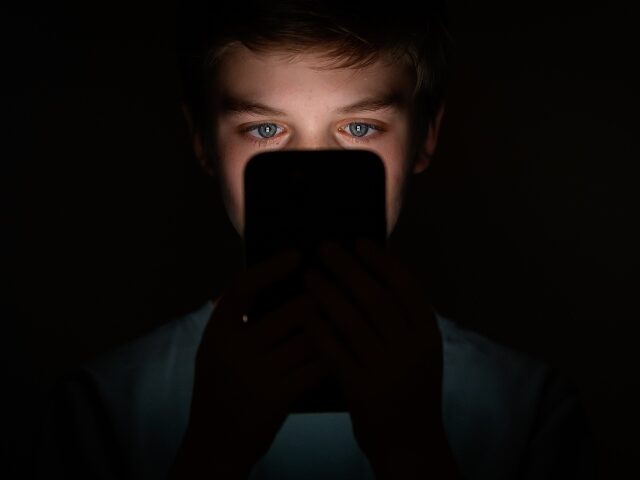 a teenager staring at his smartphone