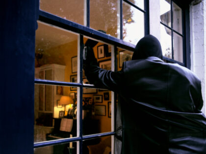 A burglar breaks into a house by smashing a window.