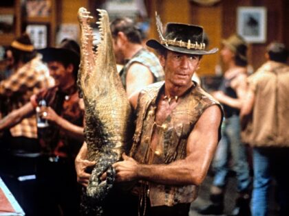 Paul Hogan carrying dead crocodile in bar in a scene from the film 'Crocodile Dundee', 198