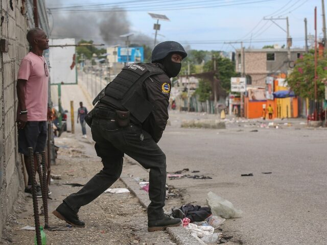 A police officer looks on during an exchange of gunfire between gangs and police in Port-a