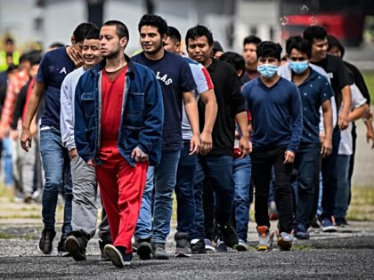 Guatemalan migrants deported from the United States walk on the airport runway upon their