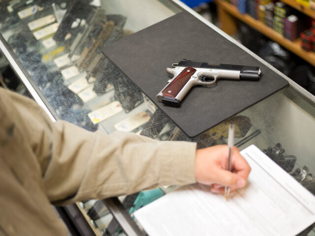 A man fills out ATF U.S. Dept. of Justice application paperwork for gun control at a gun s