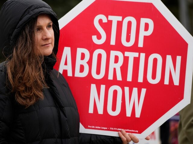 Kinga Gebauer holds a sign in front of the Walgreens corporate headquarters during a prote