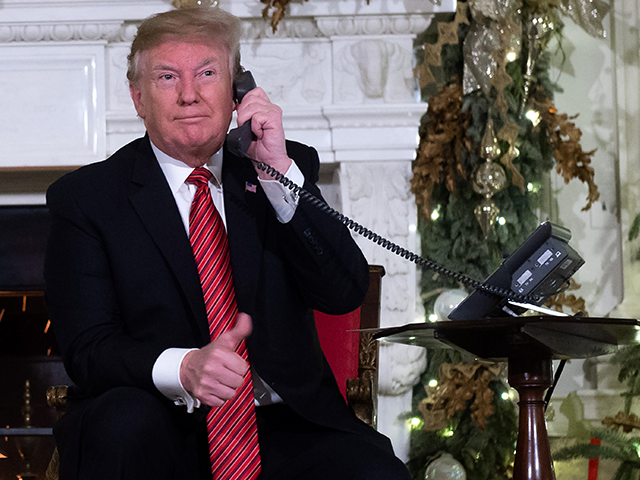 US President Donald Trump speaks on the telephone as he answers calls from people calling