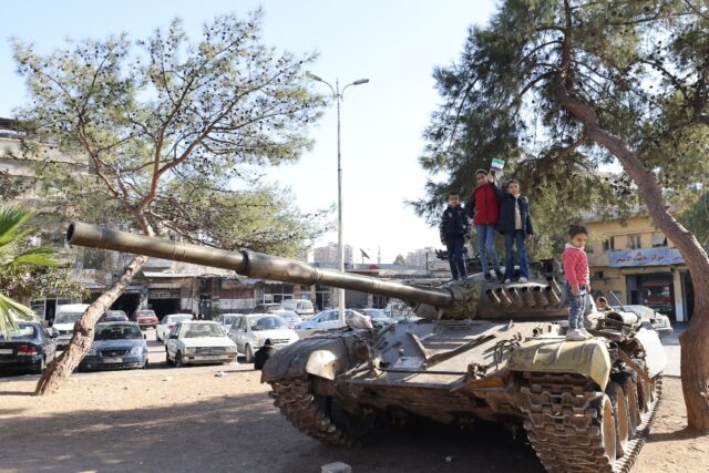 Children pose for a picture on a tank in Damascus on December 25, 2024