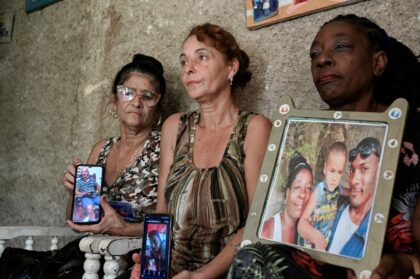 Cubans show pictures of their relatives who disappeared in January 2023 on a handmade migr