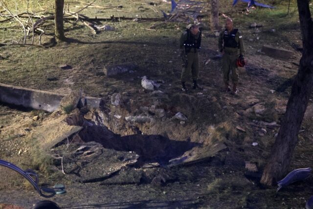 Israeli emergency responders inspect a crater at the site where a projectile fired from Ye