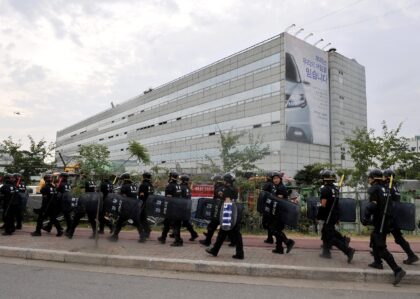 Riot police march in front of the Ssangyong offices on August 6, 2009, after massive layof