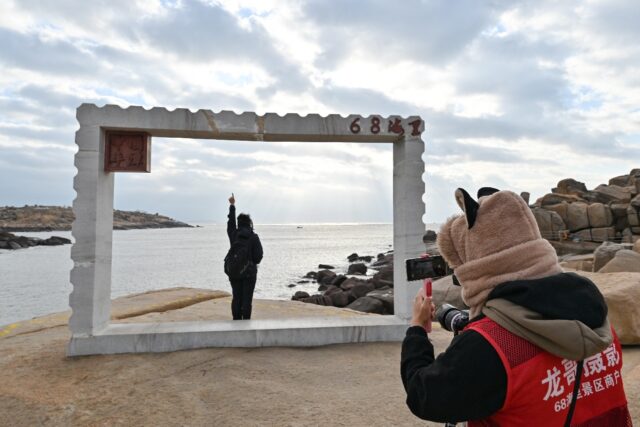 A tourist poses for a picture at a scenic spot called 68 Nautical Miles on Pingtan island,