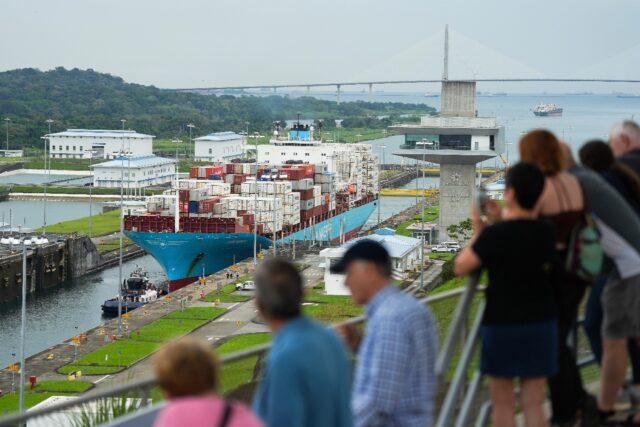 Tourists watch a Danish-flagged cargo ship passing through the Panama Canal