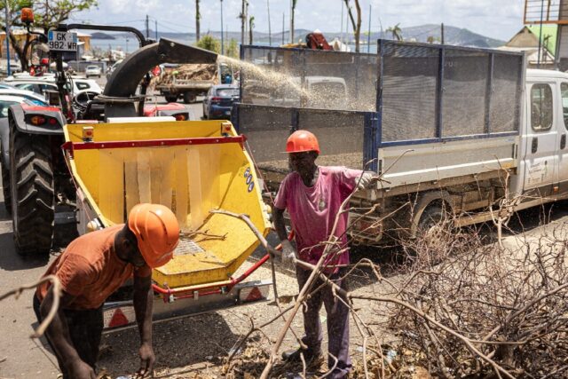 Workers clear cyclone debris from a street in Mamoudzou, the capital of Mayotte