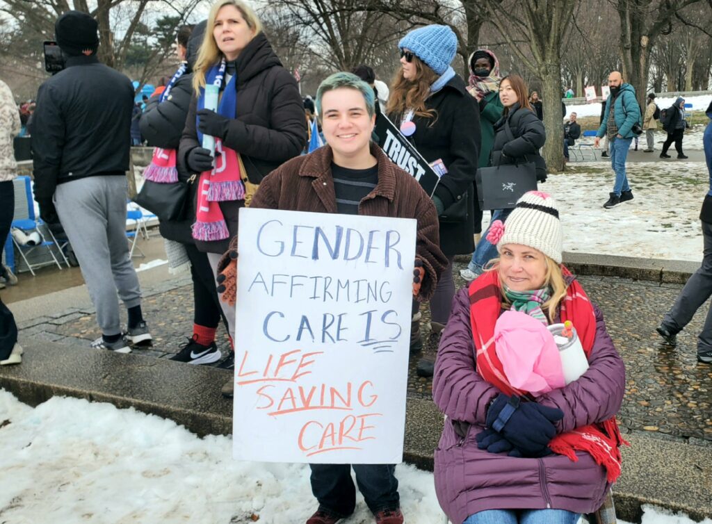 A mom looks proudly at her transgender child protesting the Trump inauguration. (Lana Shadwick/Breitbart Texas)