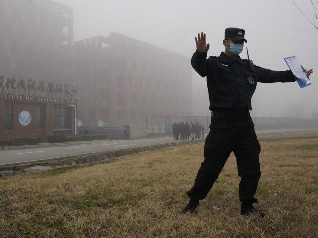 A security person moves journalists away from the Wuhan Institute of Virology after a Worl