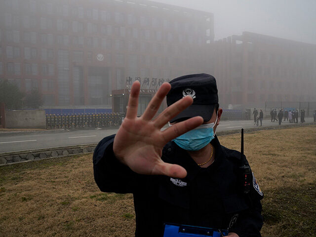 A security person moves journalists away from the Wuhan Institute of Virology after a Worl