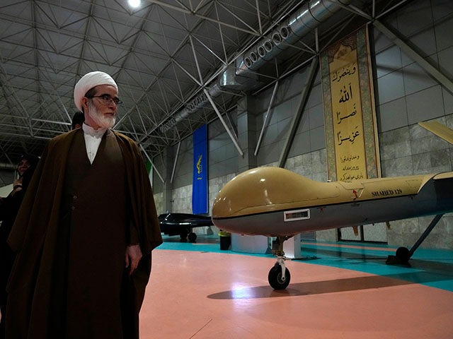 A cleric walks past an Iranian domestically-built drone as he visits National Aerospace Pa