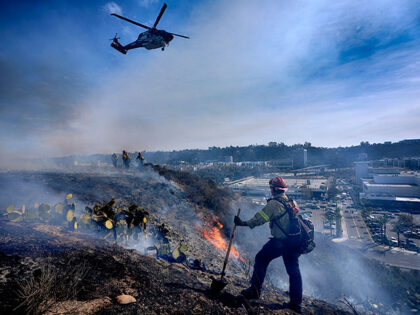 San Diego firefighters knock down a small brush along a hillside over the Mission Valley S