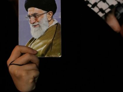 A demonstrator holds up a poster of Iranian Supreme Leader Ayatollah Ali Khamenei as she a