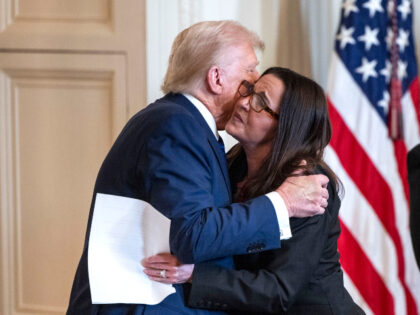 US President Donald Trump, left, and Allyson Phillips, mother of Laken Riley, embrace duri