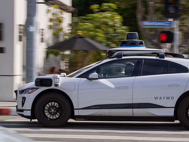 Passengers ride in an electric Jaguar I-Pace car outfitted with Waymo full self-driving te