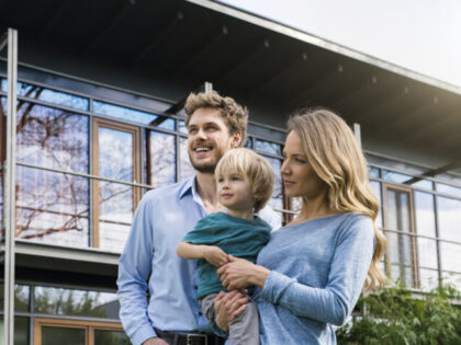 Germany, portrait of smiling family of father, mother and cute toddler boy standing in gar