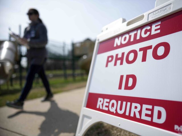 FILE - A Super Tuesday voter walks past a sign requiring a photo ID at a polling location,