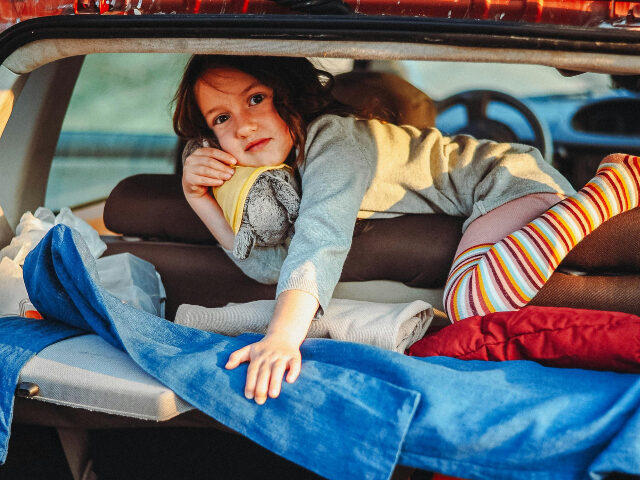 child in makeshift bed in car