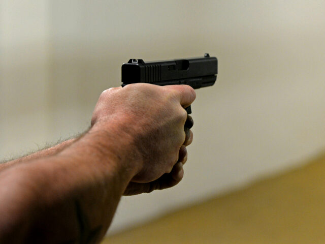 man's arm with hand pointing a gun