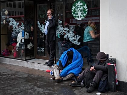 LONDON, ENGLAND - DECEMBER 07: Two homeless people sleep sitting in front of Starbucks cof