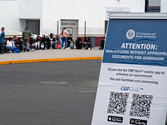 Asylum seekers queue at the El Chaparral crossing port to attend their appointment with US