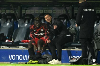 Bayer Leverkusen forward Victor Boniface (L) speaks with coach Xabi Alonso