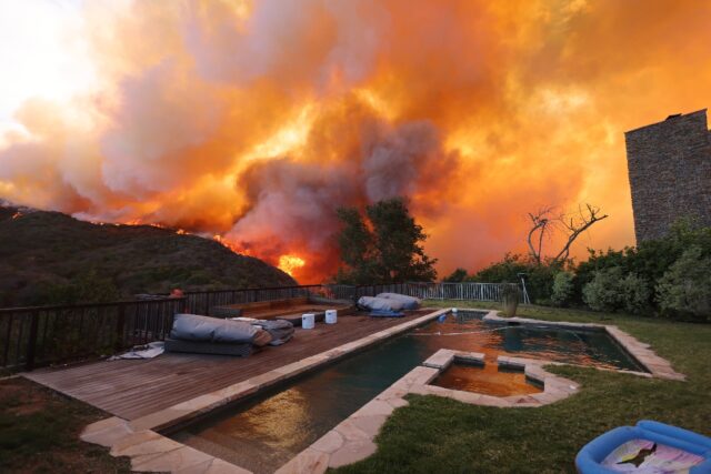 A brush fire burns near homes in upscale Pacific Palisades, California on January 7, 2025