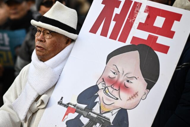 A man carrying a placard with a comic depicting South Korea's impeached president Yoon Suk